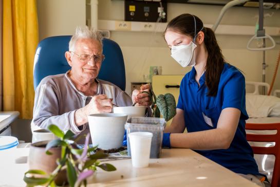Persoon op de afdeling Geriatrie verpot een plant